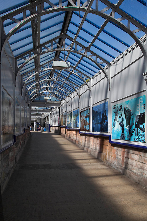 Covered walkway, Port Glasgow station 
 This delightfully restored covered walkway is at Port Glasgow station. It goes from the corner of Princess Street up to the ticket office and platform seen at the top in this image. It contained many pieces of local artwork, and with the sun streaming through from a clear blue sky as seen here it was a lovely piece of railway architecture. 
 Keywords: Covered walkway Port Glasgow station