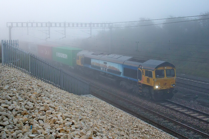 66709, 03.15 Felixstowe North-Trafford Park (4M18, 20E), Ashton Road bridge 
 66709 'Sorrento' emerges from the gloom approaching Roade leading the 4M18 03.15 Felixstowe to Trafford Park Freightliner service. This member of the class wears a one-off livery applied by GBRf to mark its contract with MSC (Mediterranean Shipping Company). It includes the image of a container ship image on a light blue background. Between the doors and the cab ends it has Europorte style semi-circles in blue and red on an orange/yellow background. 
 Keywords: 66709 03.15 Felixstowe North-Trafford Park 4M18 Ashton Road bridge Sorrento