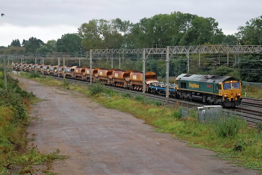 66534, 09.05 Hanslope Junction-Bescot Yard (6Y61, 84E), site of Roade station 
 A tatty set of infrastructure wagons including some HQAH Autoballasters pass through Roade having completed overnight work on the fast lines near Wolverton. 66534 OOCL Express leads the ensemble as the 6Y61 09.05 Hanslope to Bescot Yard that had initially gone south to Bletchley Yard for the locomotive to run round and head north again. 
 Keywords: 66534 09.05 Hanslope Junction-Bescot Yard 6Y61 site of Roade station OOCL Express Freightliner