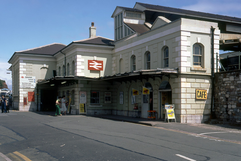 Frontage, Dawlish station 
 The starting point and end for many a holidaymaker over the years is Dawlish station! The station is a lovely building that looks very similar to this today, except that there is another caf closer to the entrance doors in the shade next to the post box. The original station was built with one platform on the leeward side serving a single broad gauge line. In 1875 this grand new station was opened that included a lift to get customers and their luggage to and from the platforms. Ever since the station was opened, it has been a constant battle to maintain it and protect it from the ravages of the sea and no more so than when disaster struck in February 2014 with the passage of a major Atlantic depression. Since then, Network Rail and its contractors have been rebuilding the sea wall in this area and have grand plans for improving the resilience of the station itself; let's hope that this does not spoil the aesthetics of the building. 
 Keywords: Frontage Dawlish Station