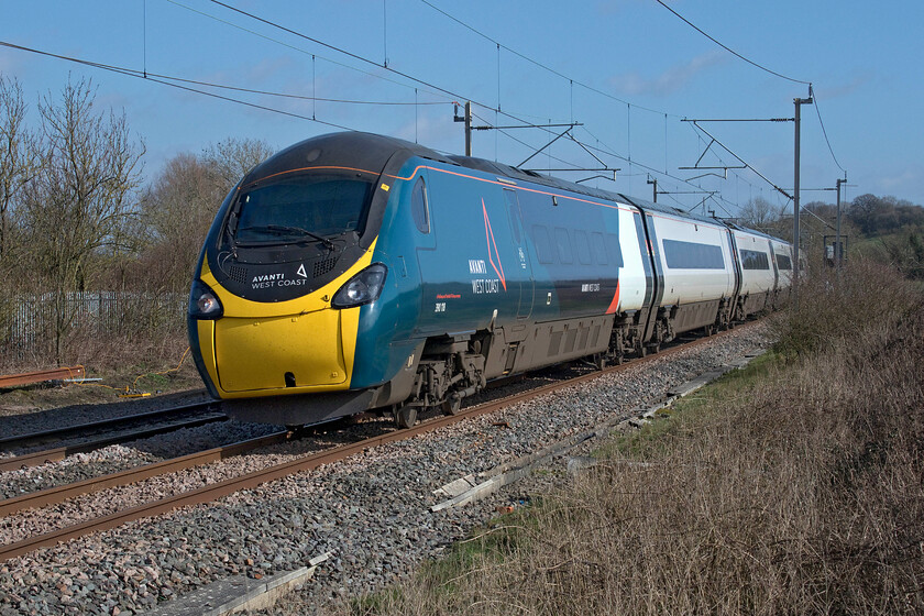 390118, VT 13.07 London Euston-Liverpool Lime Street (1F17, RT), Bugbrooke footbridge 
 After an overcast morning with showers the weather has perked up and it is decidedly spring-like! 390118 passes near Bugbrooke in Northamptonshire working Avanti's 13.07 Euston to Liverpool 1F17 service. Just behind the trees to the left is the Grand Union Canal that I had just walked along as my permitted COVID bout of exercise before stopping off to take some railway photographs. 
 Keywords: 390118 13.07 London Euston-Liverpool Lime Street 1F17 Bugbrooke footbridge Avanti West Coast Pendolino