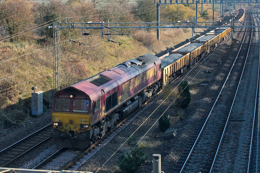 66122 & 66100, 11.30 Willesden West London Junction-Bescot Up Engineers Sidings, Ashton Road bridge 
 I have taken very few pictures from this bridge for two reasons. Firstly, it's a very narrow bridge with no pathway and cars have to get pretty close. Secondly, the parapet is so high that as a person of challenged height, I have no chance of seeing over it without a ladder and that is not practical or safe because if the first point! However, my new Canon GX1 Mk.III camera has a superb flip-out screen meaning that I can raise the camera above my head with fully stretched arms, point it over the parapet and take pictures like this! 66122 leads the 11.30 Willesden West London Junction to Bescot ballast working. At the rear of the train is 66100 'Armistice 100 1918 - 2018' that received its plates only a week earlier to commemorate the centenary of the end of World War 1. 
 Keywords: 66122 66100 11.30 Willesden West London Junction-Bescot Up Engineers' Sidings Ashton Road bridge