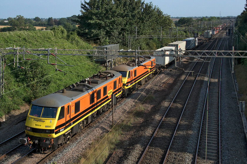 90047 & 90010, 11.13 Felixstowe North-Trafford Park (4M87, RT), Victoria bridge 
 In absolutely glorious early autumn afternoon lighting Freightliner's 90047 and 90010 pass Victoria bridge just south of Roade. The two Class 90s leading the 4M87 11.13 Felixstowe to Trafford Park service wear their recently applied and very smart Genesee and Wyoming paint scheme that is certainly an improvement of their rather drab and long in the tooth Freightliner green! I have photographed 90010 a number of times in various liveries during its time working on the GEML for Greater Anglia, for example, at Norwich back in 2014 when it was named 'Bressingham Steam & Gardens', see.... https://www.ontheupfast.com/p/21936chg/29952522604/bressingham-steam-gardens 
 Keywords: 90047 90010 11.13 Felixstowe North-Trafford Park 4M87 Victoria bridge Freightliner