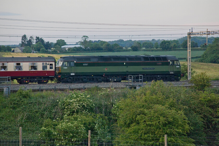 D1924 (47810), return leg of The Royal Charter, 18.13 Windsor & Eton Riverside-Crewe (1Z70, 3L), Roade Hill 
 Dead in tow at the rear of The Royal Charter D1924 'Crewe Diesel Depot' is seen in the very poor half-light on a dull early summer's evening. Running as 1Z70 the train left Windsor & Eton Riverside at 18.13 returning to Crewe with 70000 'Britannia' leading the train throughout in both directions. Now painted in a reproduction British Railways green livery, D1924 was formally numbered 47810 and wore a DRS paint scheme, for example, see..... https://www.ontheupfast.com/p/21936chg/30014430469/x47810-northern-belle-07-07-liverpool 
 Keywords: D1924 47810 return leg of The Royal Charter 18.13 Windsor & Eton Riverside-Crewe 1Z70 Roade Hill Crewe Diesel Depot