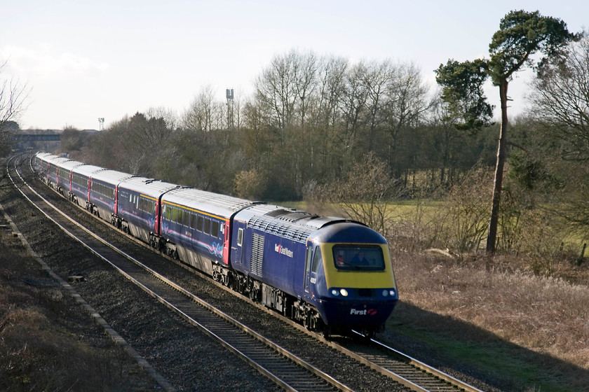 43193, GW 13.55 Cardiff Central-London Paddington (1L65), Ashbury Crossing SU246878 
 In the dying afternoon sunshine, 43193 passes Ashbury Crossing near Shrivenham leading the 1L65 13.55 Cardiff Central to Paddington express. I have deliberately taken the picture slightly off-centre to include the unusual tree standing somewhat isolated to the right. It appears to be a Scott's pine tree that was usually associated with the locations of GWR stations. But, as there was never a station here with Shrivenham's station located just behind the road bridge in the distance I am not sure why it is here? 
 Keywords: 43193 13.55 Cardiff Central-London Paddington 1L65 Ashbury Crossing SU246878