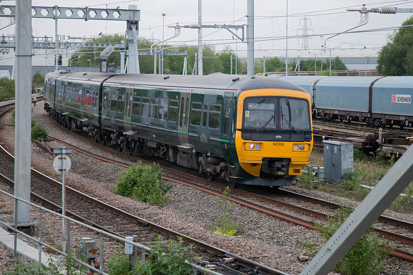 165106, GW 12.37 Oxford-London Paddington (1P52, RT), Didcot Parkway temporary car park footbridge 
 Taken from the temporary footbridge built at the western end of Didcot station 165106 arrives on the spur from North Junction with the 12.36 Oxford the Paddington. The new livery that has been applied to these units, and much of the GWR stock, does not photograph very well. The green is too dark, particularly against a lush countryside scene and often needs a fair bit of 'Photoshopping' to get it looking acceptable. 
 Keywords: 165106 1P52 Didcot Parkway temporary car park footbridge