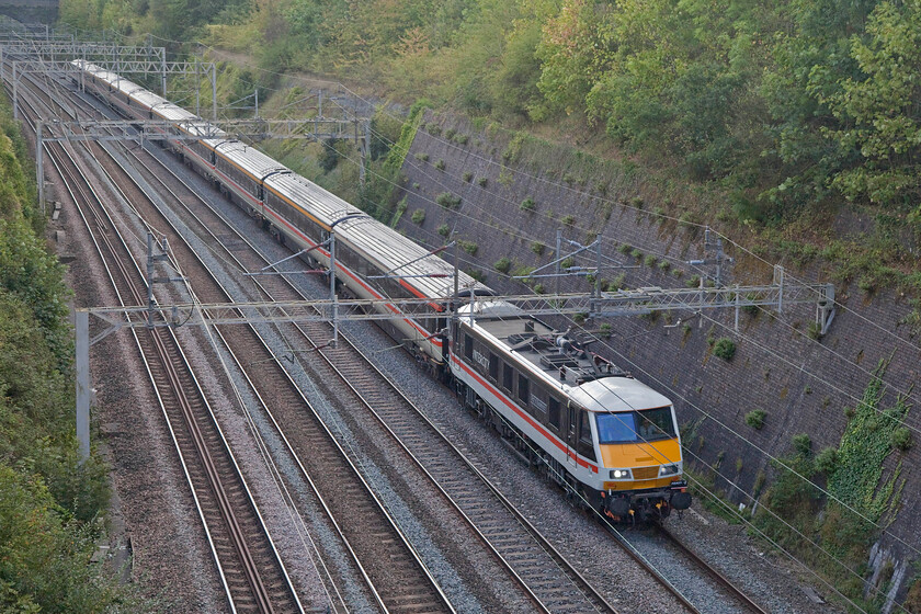 90002, 12.33 London Euston-Manchester Piccadilly (1Z84, 6L), Roade cutting 
 Having run up to London earlier in the morning, 90002 'Wolf of Badenoch' leads the returning 12.33 Euston to Manchester service running as 1Z84. The former Greater Anglia Class 90 (see.... https://www.ontheupfast.com/p/21936chg/25606768404/x90002-09-30-norwich-london-liverpool) is seen leading a matching set of InterCity Swallow liveried Mk. IIIs through Roade cutting. 
 Keywords: 90002 12.33 London Euston-Manchester Piccadilly 1Z84 Roade cutting Wolf of Badenoch LSL