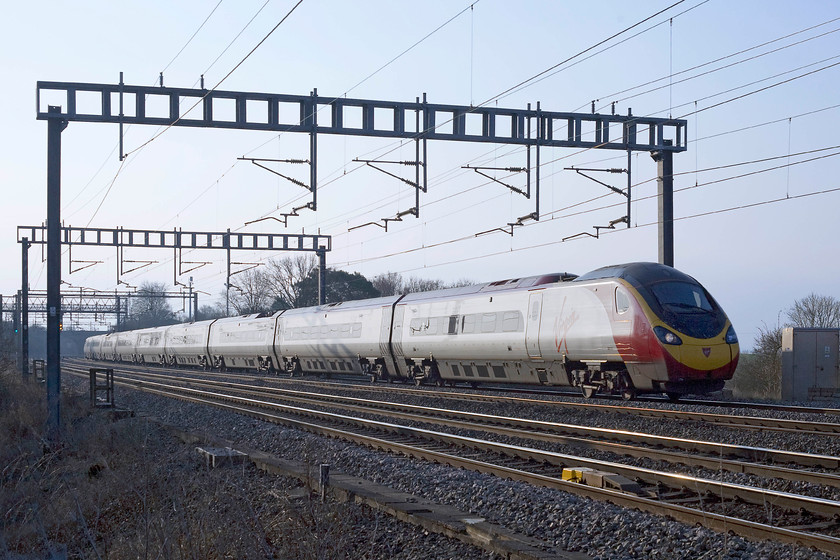 Class 390, VT 07.23 London Euston-Birmingham New Streetl (9G05), Ashton Road bridge 
 Just across the field from home south of Roade, an unidentified class 390 Pendolino works the 07.23 London Euston to Birmingham New Street. The early spring light is superb and I like the slightly backlit effect on the side of the train. 
 Keywords: Class 390 07.23 London Euston-Birmingham New Street 9G05 Ashton Road bridge