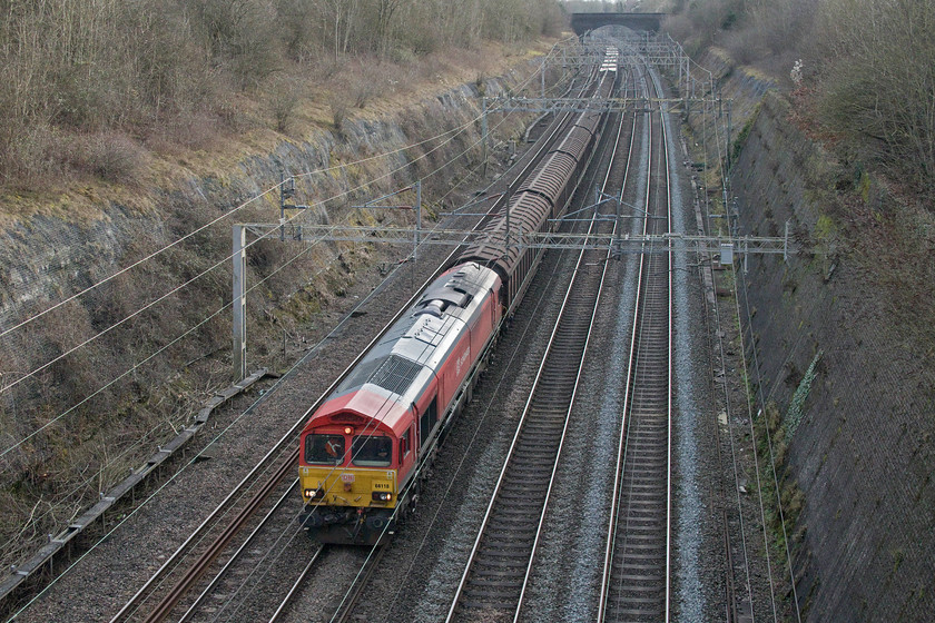 66118, 11.29 Dollands Moor-DIRFT (1E), Roade cutting 
 This working, seen passing through Roade cutting, is a bit of a mystery. As the 11.29 Dollands Moor to Daventry, there is no mistake but its reporting number is unclear. Despite my friend Mike doing some research for me (thanks!) he could not come up with a credible headcode. It should have been the daily 6M45 but it is too short, too early and also has some boxes on the rear rather than the more usual long rake of Cargo Wagons. If anybody can advise me with some more details of this working, please do get in contact with me. 
 Keywords: 66118 11.29 Dollands Moor-DIRFT Roade cutting DB