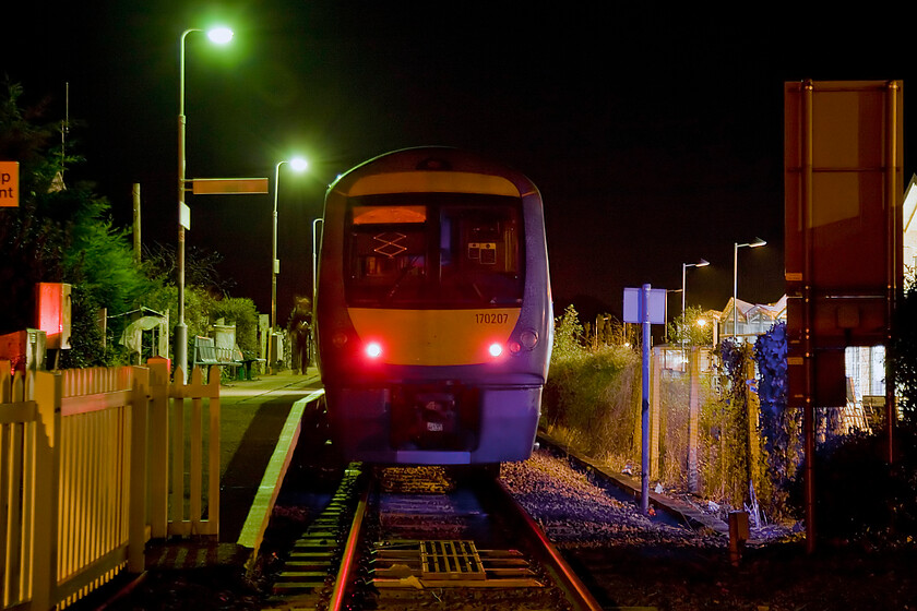 170207, LE 17.52 Sheringham-Norwich (2S25), Sheringham station 
 I really like the rather lurid and vaguely psychedelic lighting in this photograph taken behind the buffer stops at Sheringham station! It shows 170207 that my wife, son and I have just arrived on from Norwich. With the guard walking down the length of the train and the tail lights already illuminated, it will soon depart with the returning 17.52 Abellio Greater Anglia service. 
 Keywords: 170207 17.52 Sheringham-Norwich 2S25 Sheringham station Abellio Greater Anglia