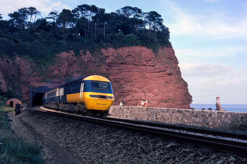 253007, 14.25 London Paddington-Penzance, Parson's Tunnel 
 Just catching a patch of evening sunshine at Parson's tunnel HST set 253007 makes its way along the sea wall working the 14.25 Paddington to Penzance service. Graham and I are quite blatantly the 'wrong side' of the fence (or the wall in this particular case) to take this photograph. We will actually have been standing on the site of the closed Parson's Tunnel signal box that was taken out of use way back in 1964. Unfortunately, I could not identify the power cars of the HST but it would have been one of either W43014 or W43015, both of which now forms part of Network Rail's NMT, see...... https://www.ontheupfast.com/p/21936chg/28656932604/x43013-43014-14-24-derby-rtc-derby 
 Keywords: 253007 14.25 London Paddington-Penzance Parson's Tunnel