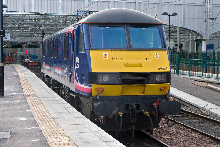 90021, stabled , Edinburgh Waverley station 
 90021 is a nocturnal locomotive seeing use on the Caledonian Sleeper services between Scotland and London. It is seen here at Waverley stabled between duties wearing its First Group and EWS liveries with its compressor gently ticking away. I can't help but think that this does not represent the best use of an expensive resource to the railways and probably goes some way to explaining why the sleeper services operate at a loss relying heavily on a considerable subsidy from the Scottish Government. 
 Keywords: 90021 stabled Edinburgh Waverley station EWS First Group Caledonian Sleeper