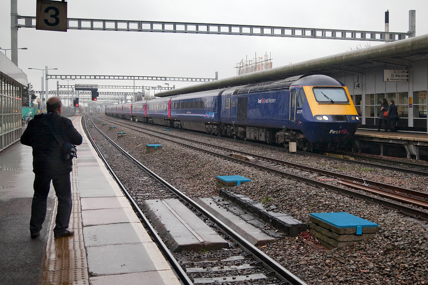 43017, GW 13.15 London Paddington-Cardiff (1B42, 1L), Swindon station 
 My good friend and spotting companion Andy shelters from the miserable rain and watches 43017 pull into Swindon forming the 13.15 Paddington to Cardiff Central working. 43017 was a very early HST delivery as part of the first batch to be put into service of the GWML from 1976. Initially, it was part of set 253008 but in the general chaos of everyday working these sets soon got broken up and mixed around! 
 Keywords: 43017 1B42 Swindon station