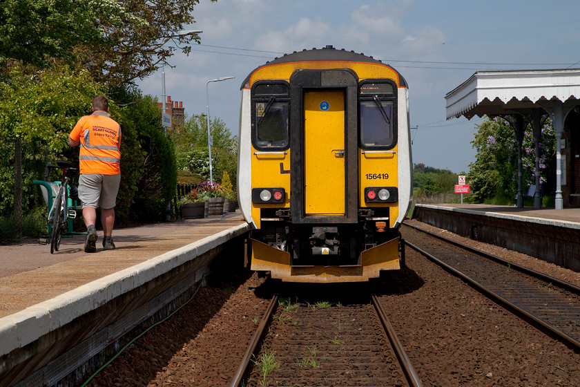 156419, LE 13.45 Norwich-Sheringham (2S20, 3L), Salhouse station 
 A sole passenger makes his way along the platform to catch the 13.45 Norwich to Sheringham at Salhouse station on the Bittern Line in Norfolk. I did not trespass when taking this shot, Salhouse station has a flat passenger crossing. However, even this crossing is monitored. There is a tiny, and quite obviously hidden, CCTV camera about the size of a dashcam, tucked in behind a sign on the down side. I gave the camera a cheery wave as I crossed safely. 
 Keywords: 156419 2S20 Salhouse station