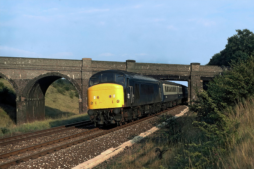 45115, 17.01 London St. Pancras-Sheffield, Souldrop SP985609 
 In glorious evening sunshine, 45115 assaults Sharnbrook Bank leading the 17.01 St. Pancras to Sheffield. This view was available until recently as a Network Rail access point was constructed here, but with the arrival of palisade fencing, it has now been rendered impossible. The bridge in the background has recently been raised and extensively remodeled to accommodate the electrification wiring. This work necessitated the closure of the bridge for some time, thus meaning the residents of nearby Sharnbrook and Souldrop had a hefty diversion to follow. I have a friend who lives nearby and he was somewhat nonplussed with the extra six miles a day added to his commute! 
 Keywords: 45115 17.01 London St. Pancras-Sheffield Souldrop SP985609