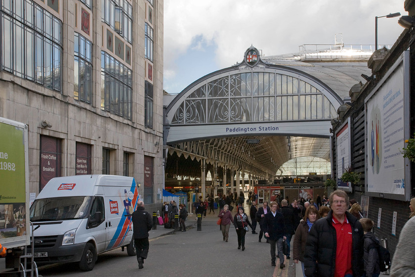 Praed Street entrance, London Paddington station 
 The entrance to Paddington station known to many who do not arrive and depart by the tube is via the short entrance ramp off Praed Street. It was commonly referred to as Carriage Road getting its name from it being the only way that road transport would enter the station. Indeed, until the station was remodelled in the 1980s it was where parcels, newspaper and taxi traffic entered the station with the vehicles actually driving on to a wide platform between trains. Praed Street is one of many eponymous roads in London being named after William Praed who was the chairman of the company which built the canal basin which lies just to the north. Notice the GWR's insignia fully restored at the apex of the arch. 
 Keywords: Praed Street entrance London Paddington station