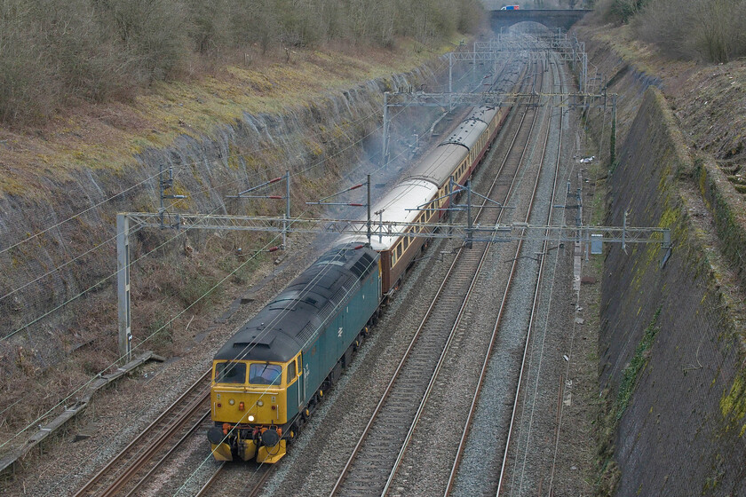 47614, 14.10 Wembley Yard-Crewe HS (5Z65, 56L), Roade cutting 
 Leaving quite a smoke stream across Roade cutting 47614 leads the 5Z65 14.10 Wembley Yard to Crewe HS empty coaching stock move. The train stock was returning to Crewe following its use on yesterday's Steam Dreams London to Settle & Carlisle Railway charter viewed yesterday at Victoria bridge, see. https://www.ontheupfast.com/p/21936chg/30040239093/x86101-london-to-settle-carlisle. The train was running to time something that it managed all the way to Basford Hall where something obviously went wrong as the final few miles from there to Crewe station for its reversal into LSLs base it ended up being nearly an hour late. 
 Keywords: 47614 14.10 Wembley Yard-Crewe HS 5Z65 Roade cutting Duff LSL Locomotive services ltd