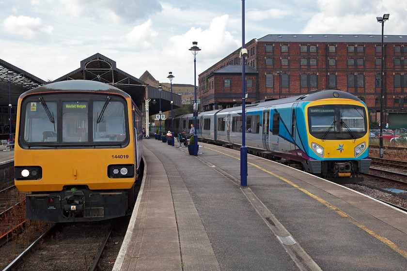 144019, NT 10.31 Huddersfield-Wakefield Westagte (2O67, 1E) & 185143, TP 09.33 Manchester Airport-Middlesborough (1P22, 1E), Huddersfiled station 
 144019 sits in one of Huddersfield's bay platforms ready to work the 10.31 to Wakefield Westgate. Meanwhile, on the right 185143 has just arrived working the Trans Pennine 09.33 Manchester Airport to Middlesborough. Notice in the background the huge St Georges Warehouse that when it was constructed between 1873 and 1883 was the largest example in the UK. It has recently undergone a huge restoration and is now in use being divided up in to various small business units. 
 Keywords: 144019 2O67 185143 1P22 Huddersfield station