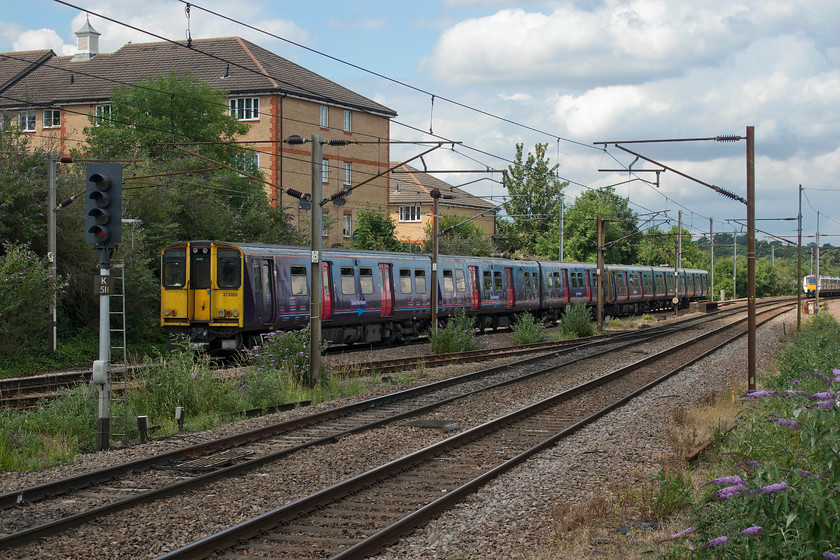 313059, GN 13.50 Moorgate-Welwyn Garden City (2V77, 1L), New Barnet station 
 313059 leaves New Barnett station as the rear set of the 13.50 Moorgate to Welwyn Garden City service operated by Great Northern. In the distance, a new class 700 is seen heading north on the down fast with a 'fast' service probably going to Cambridge. Notice that the main subject matter is in the shade with the 700 in full sun....such is the art of railway photography! 
 Keywords: 313059 13.50 Moorgate-Welwyn Garden City 2V77 New Barnet station