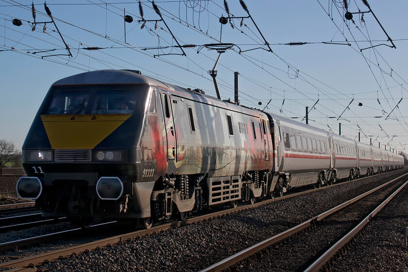 91111, GR 14.03 London King's Cross-Leeds (1D17, RT), Holme Green crossing TL192426 
 91111 'For The Fallen' makes a dramatic sight as it races at line speed along the ECML at Holme Green crossing between Arlesey and Biggleswade. The IC225 set is one of a small number retained by the state operator LNER to supplement its operations on the ECML between London, Leeds and York. In this case, this is the 1D17 14.03 King's Cross to Leeds service. If I was planning a journey between London and Yorkshire I would try to ensure that I travelled on one of the IC225 services much preferring the sumptuous luxury of a comfortably sprung and generous seat of a Mk. IV coach. 
 Keywords: 91111 14.03 London King's Cross-Leeds 1D17 Holme Green crossing TL192426 IC225 For the Fallen LNER