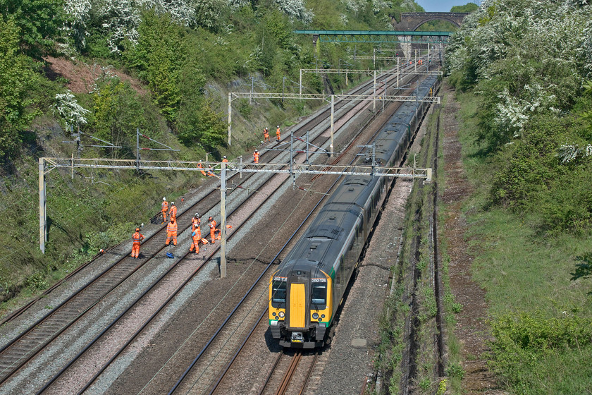 350126 & 350240, LN 11.15 Northampton-London Euston (2N32, 1E), Roade cutting 
 With the up and down fast lines still closed for maintenance during the emergency COVID-19 timetable, 350126 and 350240 work through Roade cutting with the 11.15 Northampton to Euston. I know that the fabled 'orange army' are often heralded as the heroes of the railway keeping it running but I have to say I think that their productivity is highly questionable. I stood on the bridge for about fifteen minutes and observed no work taking place except for one worker sporadically using his chainsaw. The rest spent the whole time as seen here doing nothing. It was the same story on Monday, see... https://www.ontheupfast.com/p/21936chg/29004180804/x66519-08-20-birch-coppice-felixstowe but then I put this down to it being lunchtime. Are we really getting the best value from the very expensive contracts being awarded to teams such as this to clear vegetation from the sides of the cutting? 
 Keywords: 350126 350240 11.15 Northampton-London Euston 2N32 Roade cutting London Northwestern Desiro