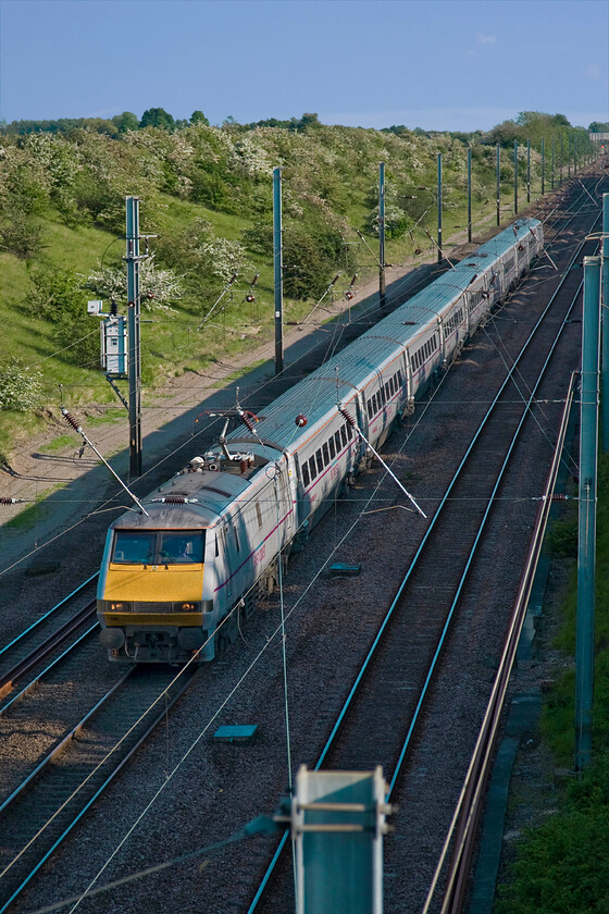 91108, GR 17.30 London King's Cross-Edinburgh Waverley (1S27), New England bridge TL219796 
 Despite it being past 18.00 the lovely evening sun is still able to illuminate a train in the depths of the cutting on the approach to Connington between Huntingdon and Peterborough. InterCity 225 91108 leads the 17.30 King's Cross to Edinburgh 1S27 East Coast service at speed on the down fast line. If anybody fancies visiting this location to take photographs or to simply observe the passage to trains you will be disappointed unless you take a step ladder as the bridge parapet is extremely high! 
 Keywords: 91108 17.30 London King's Cross-Edinburgh Waverley 1S27 New England bridge TL219796 East Coast IC 225