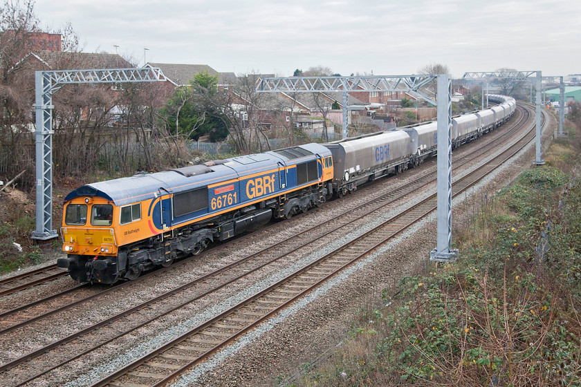 66761, 09.47 Neasden Charrington-Bardon Hill (6M32), Headlands bridge 
 66761 'Wensleydale Railway Association 25 Years 1990-2015' heads the 6M32 09.47 Neasdon to Bardon Hill empty stone train past Headlands bridge in Kettering. Even though the masts are spoiling the view from this classic spot, at least Network Rail have been busy clearing the lineside trees making this wide angle view possible. 
 Keywords: 66761 09.47 Neasden Charrington-Bardon Hill 6M32 Headlands bridge