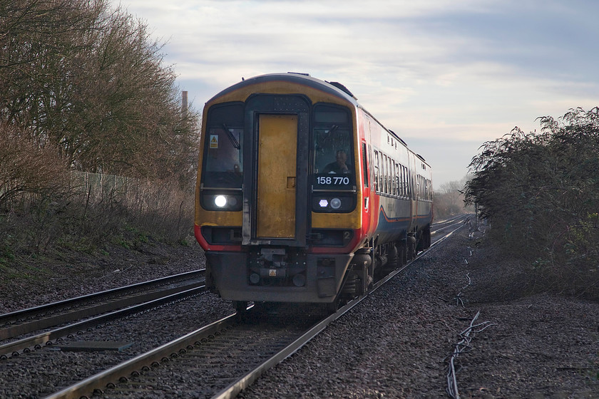 158770, EM 07.57 Norwich-Liverpool Lime Street (1R70, 1L), Kings Dyke crossing 
 Under a wintery sky, 158770 works the 1R70 07.57 Norwich to Liverpool Lime Street service. It is seen approaching Kings Dyke (or King's Dike as it is known locally) just to the east of Peterborough. Despite the extra effort involved, I like photographing in winter, when the sun is out the quality of light is very special but it does require the camera's (and the photographer's for that matter!) capabilities to be stretched somewhat. 
 Keywords: 158770 07.57 Norwich-Liverpool Lime Street 1R70 Kings Dyke crossing East Midlands Railway EMT