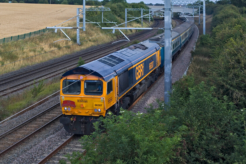 66307, outward leg of The End of the Line, 05.56 East Midlands Parkway-Newport Docks (Sims Group) (1Z39, RT), Irchester SP927667 
 Unfortunately, this photograph of UK Railtours' The End of the Line charter is not as planned; as is too often the case in our business! The 06.56 East Midlands Parkway to Newport Docks, running as 1Z39, was shown on RTT to be running on the up fast from Kettering and Wellingborough. But, as can be seen, it was pathed on to the slow line spoiling my plans! Also, the unexpected sun that had provided some dramatic lighting for the photos taken just minutes earlier had all but disappeared behind cloud. GBRf's 66307 'Ipswich Town' is leading the charter that was to end up in the Newport Docks complex visiting, as far as it dares, the sidings of Sims Group. This is rare track and would give passengers a chance to see progress being made on the breaking and recycling of various trains that end up there for scrap. Unfortunately, in addition to the issues with regard to this photograph mentioned earlier, the going away shot also failed which would have shown 66708 'Glory to Ukraine' at the rear of the train! 
 Keywords: 66307 The End of the Line, 05.56 East Midlands Parkway-Newport Docks Sims Group 1Z39 Irchester SP927667 GBRf Ipswich Town