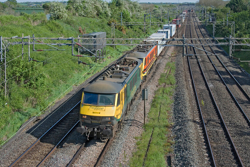 90043 & 90006, 11.32 Felixstowe North-Ditton (4M87, 4E), Victoria bridge 
 As is common practice, the 4M87 11.32 Felixstowe to Ditton Freightliner service is seen passing between Roade and Ashton double-headed. Today on this glorious spring afternoon, perhaps heralding the start of some decent weather, 90043 leads 90006 'Roger Ford'. The contrast between the earlier green livery and the more recent orange makes for a stark contrast. 
 Keywords: 90043 90006, 11.32 Felixstowe North-Ditton 4M87 Victoria bridge Freightliner Roger Ford