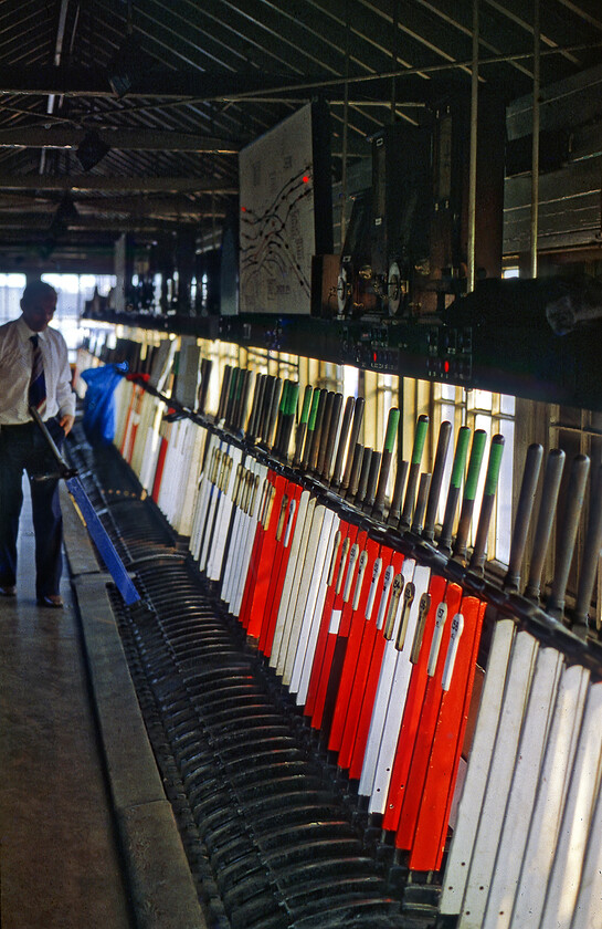 Interior, Chester No.4 signal box 
 Over time I have forgotten how Graham and I were invited into the huge Chetser No. 4 signal box. However, to prove that we were here is a photograph of the interior looking along the length of the impressive one hundred and seventy-six lever frame. By this stage of its operating life with just three years left in use, there are many levers painted white and out of use. One of the two signalmen on duty looks like he has just pulled off a blue lever that would control some sort of ground frame. I am not at all sure what the green tape wrapped around the handles of some of the levers was for. 
 Keywords: Interior, Chester No.4 signal box number 4 no4