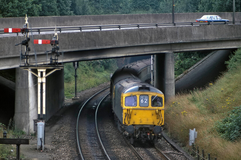 33113, 10.10 London Waterloo-Salisbury (1L83), leaving Salisbury Tunnel 
 With its jumper cables clear to see this Class 33 is easily identified as one of the nineteen push-pull-enabled 33/1 locomotives used to haul and push the 4TC units on the non-electrified section of track between Bournemouth and Weymouth. They were not used exclusively on this route and were often found elsewhere as is the case here with 33113 approaching Salisbury leading the 1L83 10.10 Waterloo to Salisbury sem-fast service. Notice the lone car, a Mk. II Ford Granda, on the A36 Salisbury inner relief road. How often today on a Saturday morning would just one car be seen on this very busy piece of road? 
 Keywords: 33113 10.10 London Waterloo-Salisbury 1L83 leaving Salisbury Tunnel Crompton