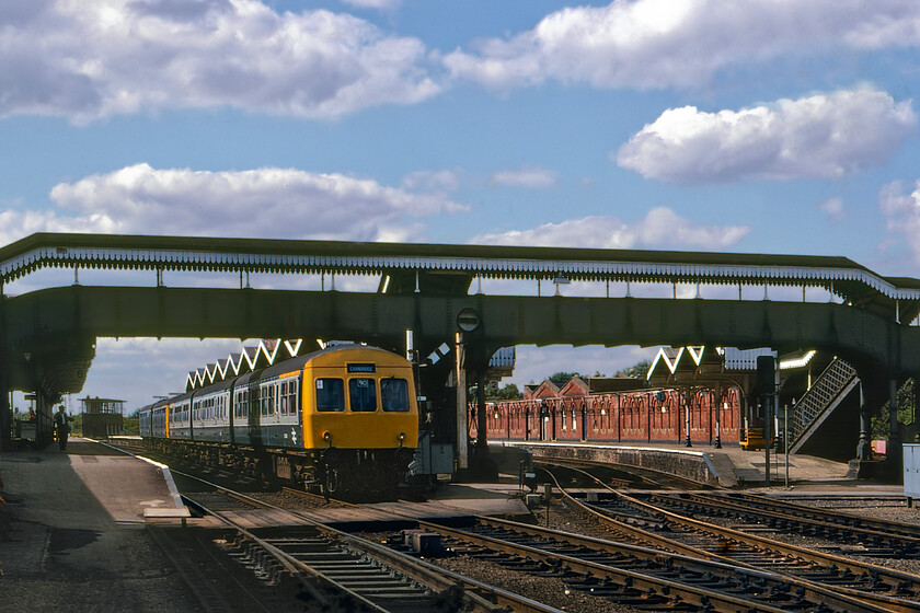 Class 101 & Class 105 DMU, 14.05 Peterborough-Cambridge, March station 
 The 14.05 Peterborough to Cambridge service is seen leaving March station worked by Class 101 DMU leading a Class 105 on the rear. Along with Class 31 locomotive-hauled services DMUs operated the majority of trains in this part of East Anglia and the Fens. Notice in this view that March station still had all four platforms in operation with just the two to the left having tracks laid today. The platforms to the right served passengers and traffic travelling via the GN&GEJR to Spaldingand the Wisbech branch both of which have now succumbed. However, there are constant rumblings about the reopening of the latter route in some form or another. 
 Keywords: Class 101 Class 105 DMU 14.05 Peterborough-Cambridge March station first generation dmu