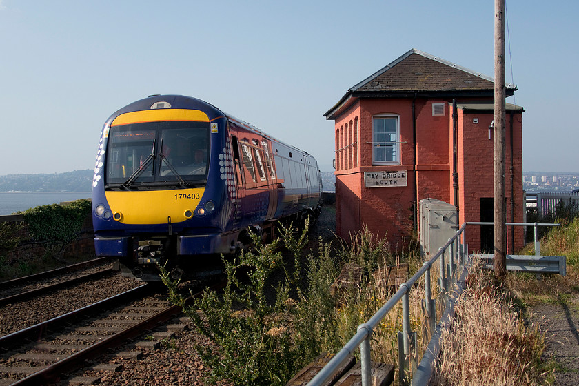 170403, SR 15.59 Arbroath-Edinburgh Waverley (2L60, RT) & Tay Bridge South signal box (NB, 1897) 
 With the Firth of Tay in the background, 170403 comes off the famous bridge forming the 15.59 Arbroath to Edinburgh service. The 1897 signal box, unlike a number of the other North British structures in the area, has not had its looks too badly wrecked by the addition of UPVC cladding, but it has had its brickwork painted in an awful red/orange paint. This must be an amazing place to be a signalman, affording superb views across the estuary with the city of Dundee just visible to the right of the box. 
 Keywords: 170403 15.59 Arbroath-Edinburgh Waverley 2L60 Tay Bridge South signal box