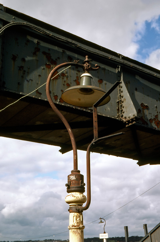 Ex GWR lamp (Thorlax), Starcross station 
 A remarkable survivor on Starcross station back in 1980 was these former GWR lamps on each platform. They were manufactured by Thorlux who are still making electrical lighting and fittings today at their state of the art factory in Redditch. I suspect that their catalogue today does not contain such elaborate or ornate products like these fine lamps! 
 Keywords: Ex GWR lamp Thorlax Starcross station