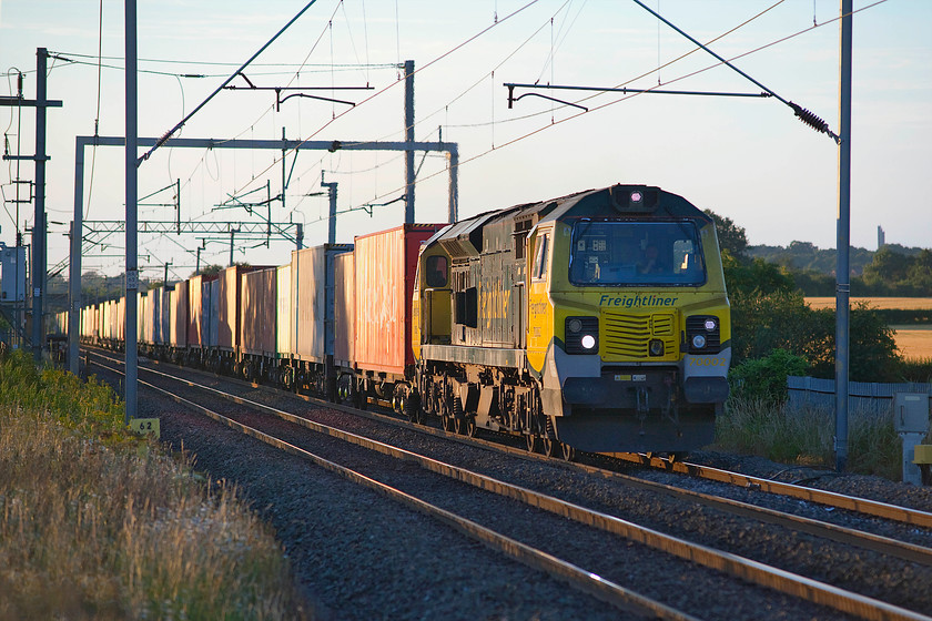 70002, 16.15 Trafford Park-Felixstowe North (4L96), Milton Malsor 
 70002 was only a short distance and a few minutes behind the previous freight here and Milton Malsor between Northampton and Roade. It is leading the Friday only 16.15 Trafford Park to Felixstowe North. The picture is taken from the top of my ladder leaning against the palisade fencing that is of a slightly unusual type with no spikes on the top. Taken using my Sigma 80-200 zoom lens has brought the unusual spire of West Hunsbury's St Benedict's Church into the image on the far right. 
 Keywords: 70002 16.15 Trafford Park-Felixstowe North 4L96 Milton Malsor