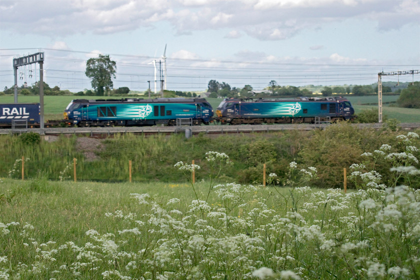 88010 & 68016, 14.10 DIRFT-Mossend (4Z45, 147L), Roade Hill 
 Just as the diverted 14.10 DIRFT to Mossend 'Tesco Express' approached my location on Roade Hill the sun dived behind a large cloud. Rather than take another disappointing shaded photograph I went down on my haunches and focused on the cow parsley (Anthriscus sylvestris) in the foreground to alter the interest slightly. I would have liked a little more of the cow parsley and the train to be in focus but at 1/2000 sec shutter speed, there was not enough depth of field at the aperture (f5.6). With a little more time I could have ramped the ISO up from 500 to perhaps 1600 and that would have got the depth of field required to get more of the image in focus. 88010 'Aurora' leads 68016 'Fearless' on the heavily diverted and late working service that is heading south to London before then heading north up the ECML to Scotland. 
 Keywords: 88010 68016 14.10 DIRFT-Mossend 4Z45 Roade Hill Aurora Fearless DRS Direct Rail Services Tesco Express