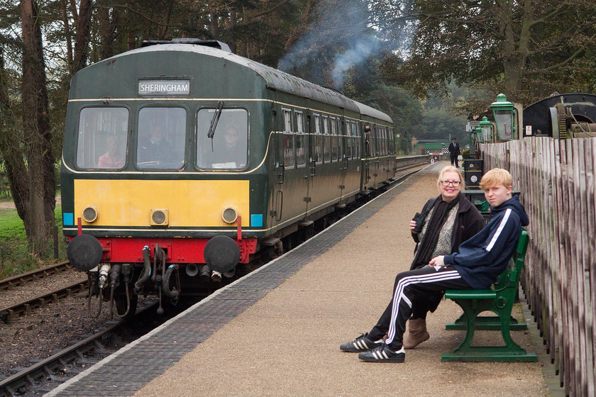 M56352 & M51192, 12.15 Holt-Sheringham, Holt station 
 My wife and son rest at Holt station having ridden their bikes from Kelling Heath. As they do this, the 12.15 Holt to Sheringham service leaves the station formed by M56352 and M51192. 
 Keywords: M56352 M51192 12.15 Holt-Sheringham Holt station