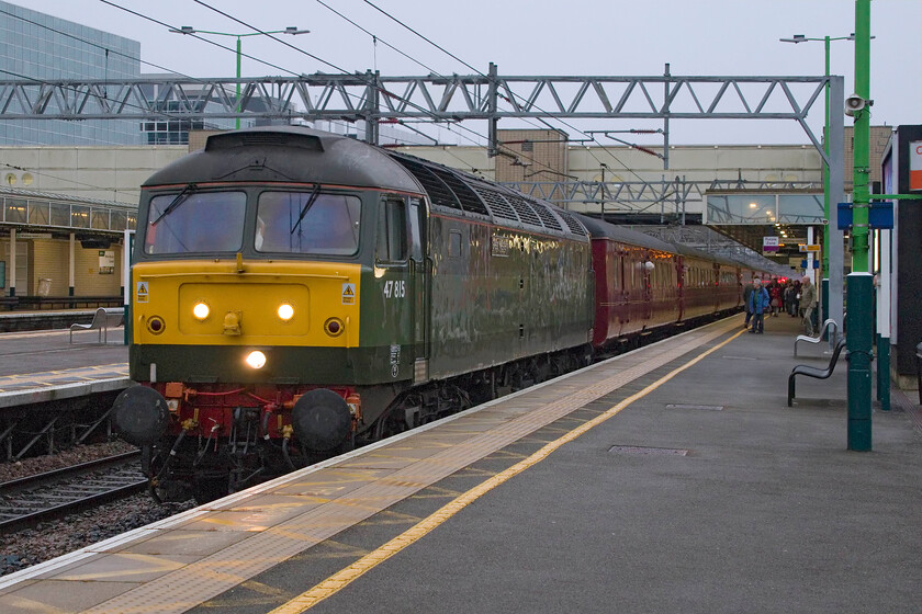 47815, outward leg of The Cumbrian Mountain Express, 06.35 London Euston-Carlisle (1Z86, 4E), Milton Keynes station 
 With 86259 'Les Ross/Peter Pan' out of action following failure working the previous Cumbrian Mountain Express on 27.01.24 West Coast Railways has been forced to substitute a diesel in the form of 47815 'Great Western' for today's charter. In addition, due to the refusal of the regulator to allow WCR to use their own Mk. 1 stock without the fitting of CDL (central door locking), they have had to hire in compliant stock that has been hastily re-branded with WCR vinyls. Still running as 1Z86 (in a nod to its usual haulage) the charter is seen arriving at Milton Keynes station on a very dull February morning. 
 Keywords: 47815 The Cumbrian Mountain Express 06.35 London Euston-Carlisle 1Z86 Milton Keynes station WCR West Coast Railway Great Western