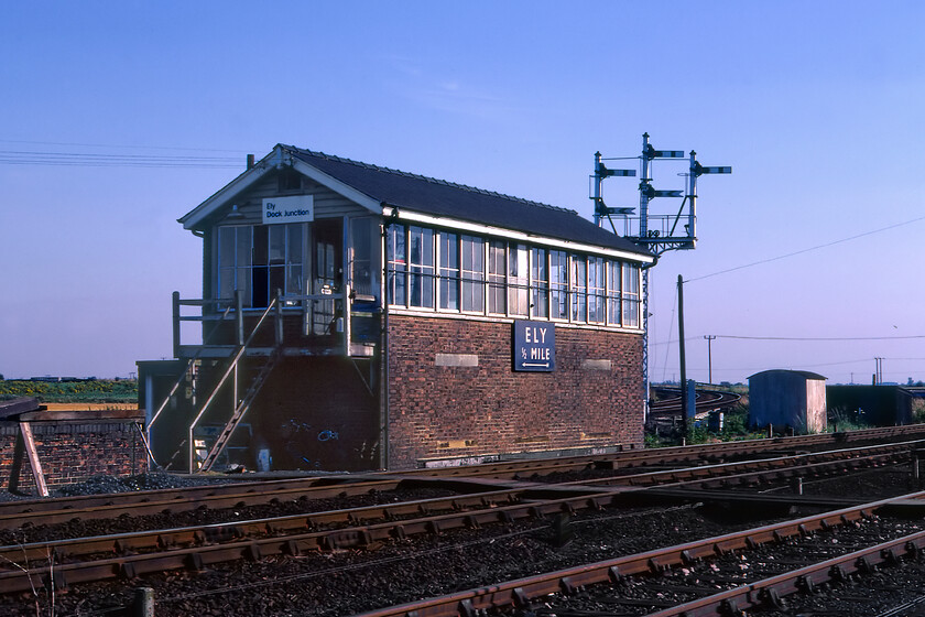 Ely Dock Junction signal box (LNER, 1928) 
 Ely Dock Junction signal box was located south of the station according to British Railways (Eastern) enamel by half a mile. It controlled the junction where the now singled track route to Snailwell Junction (now named Chippenham Junction) left the direct route to Cambridge (and ultimately London Liverpool Street). Notice the superb three-doll bracket signal just beyond the box with the down Soham arms installed including an Ely Station North signal box single line fixed distant (bottom left far left as seen). The box is an LNER Type 11a design dating from 1928 and it contained an eighty two lever Westinghouse Brake & Saxby A2 frame. It closed on 10.04.92 with it being demolished two weeks later. Interestingly, by the time it closed the large enamel sign had been replaced with a Network SouthEast version that had the station at a mile to the north. As neither the station or the signal box had moved in the intervening years I am not sure how the distance between the two had doubled! 
 Keywords: Ely Dock Junction signal box LNER London and North Eastern Railway