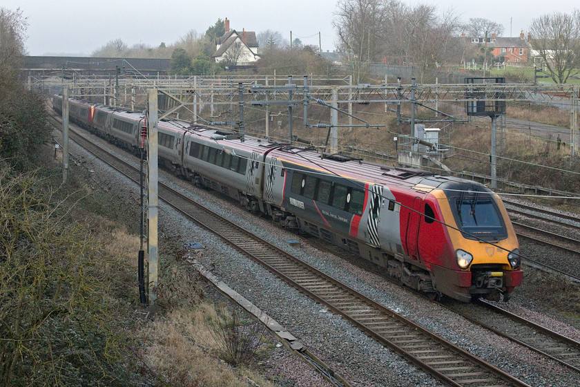 221115 & Class 221, VT 12.30 Birmingham New Street-London Euston (1B44, 15L), site of Roade station 
 With plans to replace the Voyagers now allegedly on hold due to the COVID crisis, it looks like we will have these inefficient units noisily running up and down the WCML for a while yet. This begs the question as to whether the new operator Avanti West Coast will re-paint and re-brand them removing the final vestiges of their Virgin legacy. 221115 leads another unit past the site of Roade's station with the 1B44 12.30 Birmingham to Euston. With a much-reduced timetable, why are most of these units not mothballed and the spare Pendolinos used to run fully under the wires on services such as this? 
 Keywords: 221115 Class 221, VT 12.30 Birmingham New Street-London Euston 1B44 site of Roade station Virgin Voyager Avanti West Coast