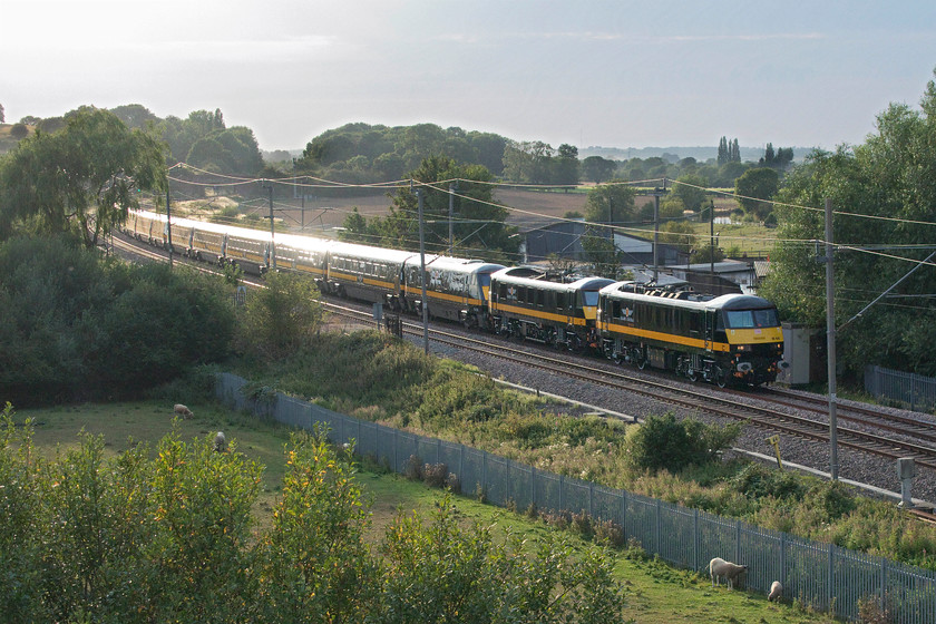 90026, 90020, 82230, 17.20 Widnes Transport Tech-Wembley Inter City depot (5Z90, 5L), Banbury Lane bridge 
 Running a few minutes late Grand Central's newly painted 90026 and 90020 lead the 17.20 Widnes Transport Tech. to Wembley Inter City depot test train running as 5Z90. It is seen in awful lighting at Banbury Lane bridge just south of Bugbrooke on the Weedon mainline. The train is formed of two complete sets of Grand Central Mk.IV stock (ex LNER) with their DVTs also in the consist. 82230 is the one directly behind the locomotives with 82201 further back. After a belting hot day it had clouded up into a humid evening. In fact, it had been raining a few minutes before the arrival of the train with the sun then conspiring to come out a minute before its passing. This has created a very backlit 'glint shot' that has needed a fair bit of Photoshop work to make it presentable. Incidentally, the train ran in reverse formation back from Wembley to Crewe in the night. Needless to say, I did not go out to see it! 
 Keywords: 90026 90020 82230 17.20 Widnes Transport Tech-Wembley Inter City depot 5Z90 Banbury Lane bridge Grand Central