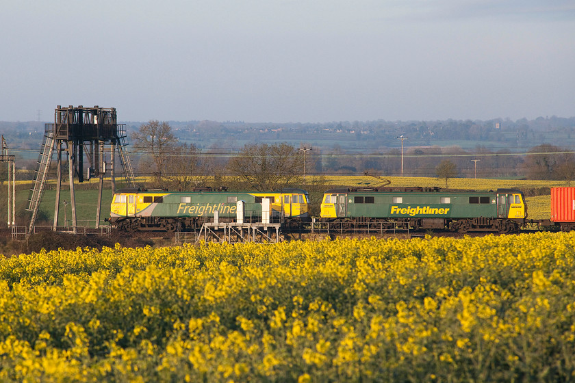 86237 & 86639, 22.01 Coatbridge-Felixstowe (4L89), between Roade & Ashton 
 This is not a working very often seen in the daylight usually passing through the Northamptonshire countryside in the middle of the night. On this morning severe delays meant that the 22.01 Coatbridge to Felixstowe hauled by veteran AC electrics 86237 and 86639 was captured in the spring sunshine passing the oilseed rape fields between Roade and Ashton. In the background is the village of Grafton Regis with its Norman tower of St. Mary the Virgin's church catching the light. 
 Keywords: 86237 86639 22.01 Coatbridge-Felixstowe 4L89 between Roade & Ashton