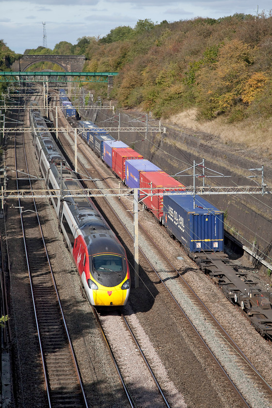 390002, VT 12.50 Birmingham New Street-London Euston (1B24, 4E) & 13.09 DIRFT-Ripple Lane (4L98), Roade cutting 
 As the 13.09 DIRFT (Daventry) to Ripple Lane Freightliner crawls through Roade cutting, 390002 'Steven Sutton' sweeps past it forming the 12.50 Birmingham New Street to London Euston. With the warm colours of the vegetation above the cutting, it can only be autumn! 
 Keywords: 390002 12.50 Birmingham New Street-London Euston 1B24 13.09 DIRFT-Ripple Lane 4L98 Roade cutting