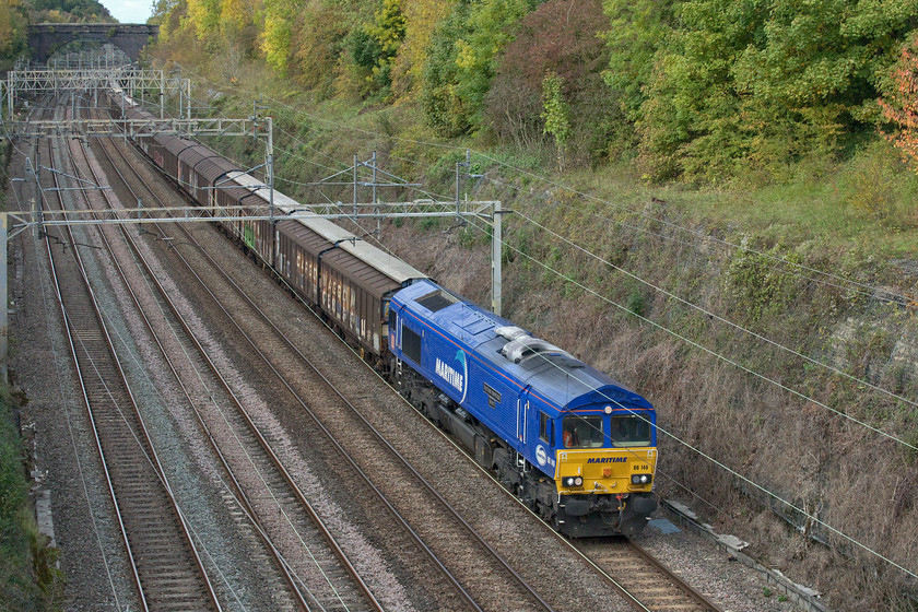 66148, 14.47 DIRFT-Dollands Moor (6M45, 1E), Hyde Road bridge 
 My second photographic 'cop' of the day is about to pass under Roade's Hyde Road bridge - well not quite strictly true! Whilst I have a number of photographs of 66148 I have none of it in its Maritime livery and since its naming. So I can tick 66148 'Maritime Intermodal Seven' off the required list with just three now to get. The locomotive has been hired in by DB to haul the daily empty water bottle train from Daventry (DIRFT) to Dollands Moor. Notice the subtly changing colour of the trees high above Roade cutting - it can only be early autumn! 
 Keywords: 66148 14.47 DIRFT-Dollands Moor 6M45 Hyde Road bridge Maritime Intermodal seven DB