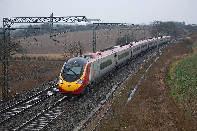 Class 390, VT 07.30 London Euston-Glasgow Central, Milton Crossing 
 In pouring rain at Milton crossing between Roade and Blisworth an unidentified Class 390 pendolino heads north working the 07.30 London Euston to Glasgow Central service. Not the finest quality photograph but I like taking images in more challenging weather showing the full range of the network's operations. 
 Keywords: Class 390 07.30 London Euston-Glasgow Central, Milton Crossing Virgin West Coast pendolino