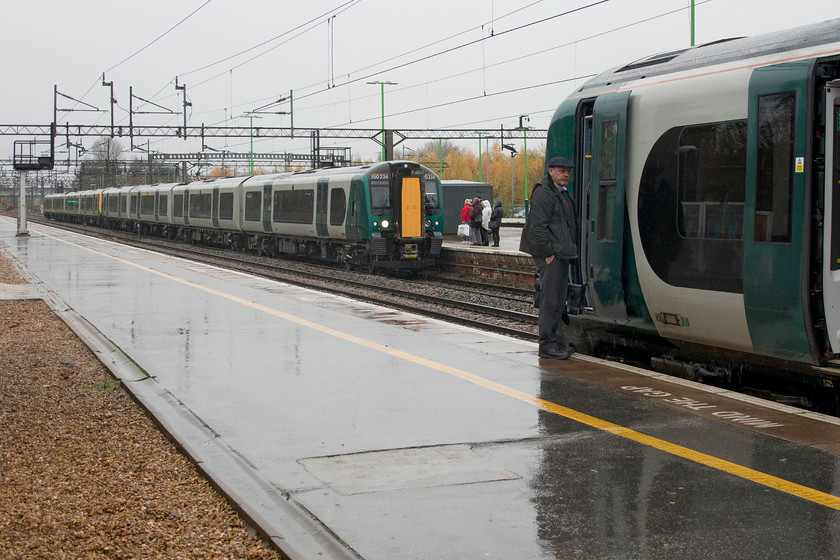 350234, LN 07.09 Rugeley Trent Valley & 06.35 Crewe London Euston (1W70, 12L) & 350253, LN 08.22 London Euston Rugeley Trent Valley (9K52, 13L), Northampton station 
 In the pouring rain at Northampton station another two late running London NorthWestern services pass. 350234 and another unit arrive at platform one with the 07.09 Rugeley/06.35 Crewe to London Euston service that will have come together at Birmingham. Meanwhile, the driver has just alighted from 350253 that has arrived as the 08.22 Euston to Rugeley Trent Valley. Both these trains were late being just below the delay-repay threshold. 
 Keywords: 350234, LN 07.09 Rugeley Trent Valley & 06.35 Crewe London Euston (1W70, 12L) & 350253, LN 08.22 London Euston Rugeley Trent Valley (9K52, 13L), Northampton station