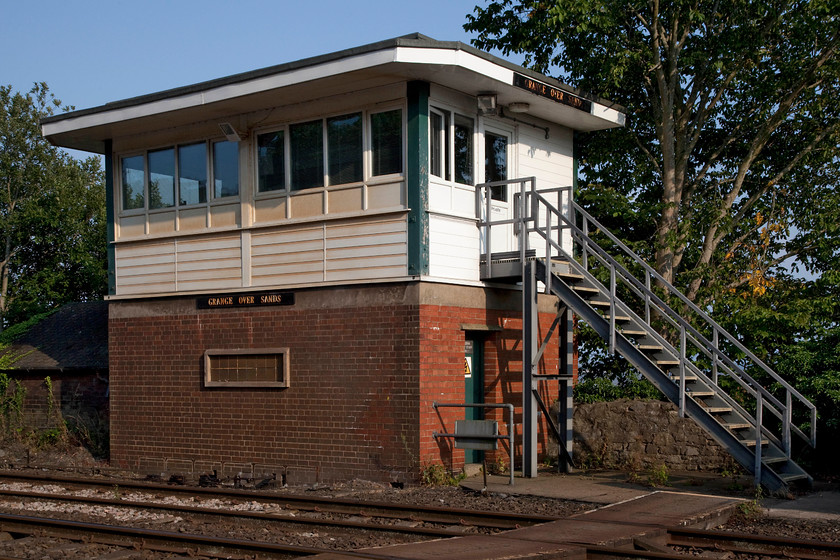 Grange-over-Sands signal box (BR, 1956) 
 Grange-over-Sands signal box was last photographed by me in 1985 on a dull and damp October day. The background was somewhat different then with no trees and it had a chimney with some smoke drifting out of it. The box is a BR Type 15 structure built in 1956 and is looking good apart from the non-standard (but H&S compliant) steps. 
 Keywords: Grange-over-Sands signal box