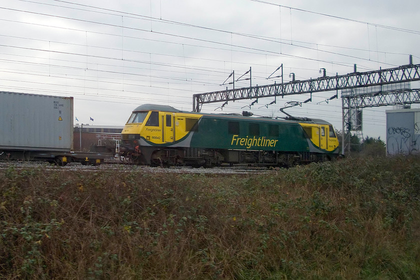 90042, 09.12 Felixstowe North-Ditton (4M63), Willesden yard 
 Technically not a great photograph and showing poor levels of composure but I have included it for its unusual location! When taking a Southern service back from the West London line to the WCML the trains pass under the latter before remerging on the east in order to access the down slow line. In doing so they pass the northern end of Willesden yard and if one is lucky a northbound freight can be seen held at a red signal waiting for the train you are on to pass. On this day, 90042 is held leading the 4M63 09.12 Felixstowe to Ditton Freightliner seen as we climb back to mainline track level and slot in front of it. Without being on a passing train there is no chance whatsoever of getting a photograph at this location hence its inclusion! 
 Keywords: 90042 09.12 Felixstowe North-Ditton 4M63 Willesden yard Freightliner