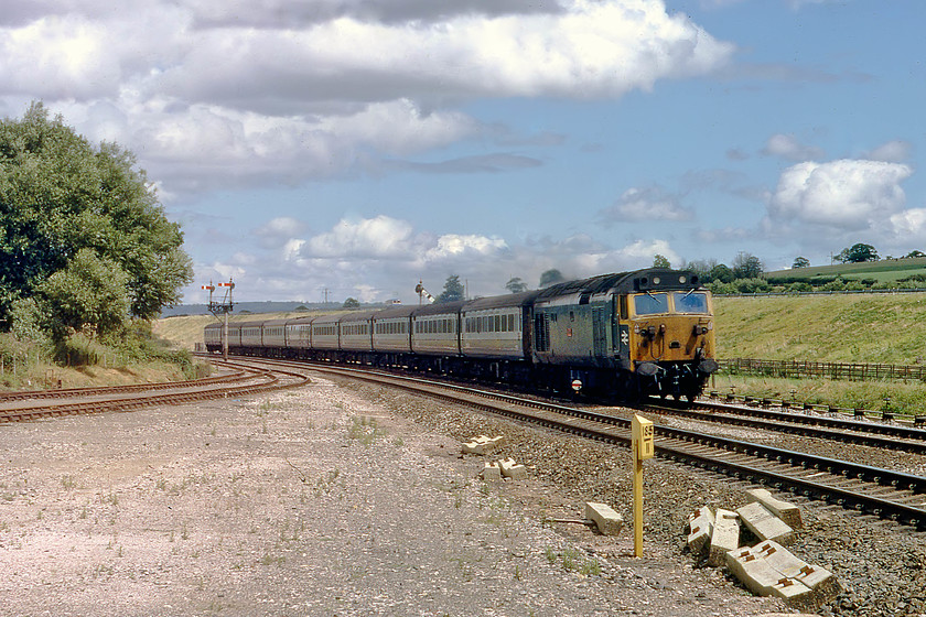 50015, 11.30 London Paddington-Penznce, The Cornish Rivera, Hele & Bradninch 
 With not a vehicle in sight on the M5 in the background, 50015 'Valiant' comes around the curve approaching Hele and Bradninch with the 11.30 London Paddington to Penzance, the down Cornish Riviera. The sidings to the left mark the point where the old station yard used to be. Note the milepost in the foreground showing 185 miles from London via the Bristol route. 
 Keywords: 50015 11.30 London Paddington-Penzance, The Cornish Rivera, Hele & Bradninc